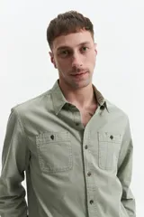 Camisa de manga larga color verde militar, corte slim fit, con cuello clásico, cierre abotonado, dos bolsillos frontales con botón y puños abotonados.
