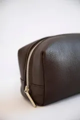 Necessaire de cuero vacuno color marrón, con cierre superior y bolsillo interno. Ideal para artículos de tocador.
