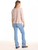 Buzo de tejido suave color beige, con cuello a la base y mangas 3/4 con aplique de botones dorados. Presenta terminación con tajos en los laterales.