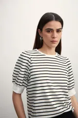 Remera de manga corta con cuello redondo y estampado de rayas horizontales blancas y negras. Mangas abullonadas con puño blanco.