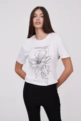 Remera blanca con estampado de hojas de ginkgo biloba en tonos naranja, beige y gris.