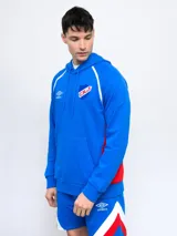 Canguro hoodie azul con capucha, cordones ajustables, bolsillo canguro y detalles en blanco y rojo en los costados y mangas. Incluye el logo de Umbro y el escudo del Club Nacional de Football en el pecho.