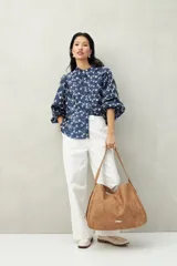Camisa blanca con bordado floral en contraste, cuello mao, abotonadura frontal y mangas largas con frunces en los hombros.