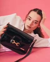 Bandolera color beige con textura símil reptil, cierre con broche metálico dorado y correa larga regulable.