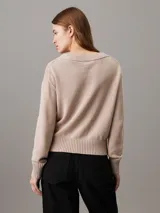 Sweater de punto color rosa pálido con cuello en V y logo bordado en el pecho.