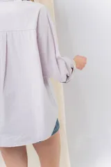 Camisa color crema de algodón liviano, calce oversize, con cuello camisero, cierre abotonado, mangas largas con opción de arremangado y dos bolsillos frontales con solapa.