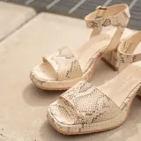 Sandalias de cuero color marrón con plataforma y tacón cuadrado. Tiras anchas sobre los dedos y tobillo con hebilla ajustable.