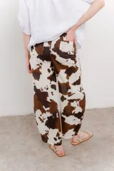 Pantalón ancho de lino con estampado de manchas de vaca en tonos marrón y blanco. Incluye cinturón de soga trenzada con flecos.