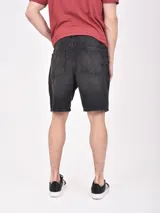 Bermuda de jean negro con roturas y corte a la rodilla.