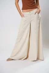 Pantalón palazzo color beige con bordados calados en forma de paisley en los laterales.