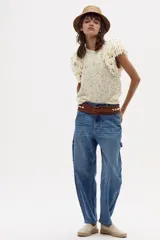 Chaleco tejido plano color crudo, sin mangas, con flecos bordados a mano en los hombros.