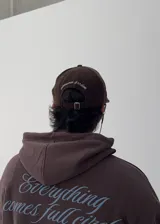 Gorro tipo gorra de béisbol color marrón, confeccionado en pana, con visera corta y bordado frontal en blanco que dice "LOVE & PEACE" y "PP:ONE".