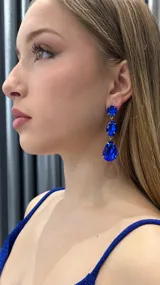 Aros colgantes dorados con tres cristales facetados de color azul zafiro en forma circular, ovalada y de lágrima.