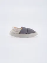 Pantuflas grises con interior de piel sintética color crema y suela blanca.