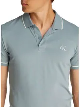 Chomba de piqué celeste con cuello polo, mangas cortas y corte slim. Presenta tapeta de dos botones, logo CK bordado en el pecho y ribetes blancos en cuello y mangas.