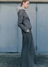 Pantalón de vestir color gris topo, de corte wide leg, tiro alto, con pinzas delanteras, bolsillos laterales y cierre frontal con botón, gancho y cremallera.