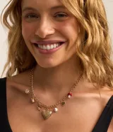 Collar corto dorado con cadena de eslabones y dijes colgantes: flor, taza, trébol, corazón, hongo y perla.