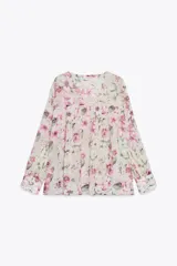 Camisa semitransparente con estampado de flores en tonos rosa y verde, cuello pico y manga larga con puños. Tiene aberturas laterales y cierre frontal con botones.
