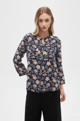 Camisa de viscosa con estampado floral en tonos azul, beige y blanco. Tiene cuello mao, mangas largas y bolsillos en el pecho.