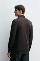 Camisa negra de manga larga con cuello italiano abierto y cierre frontal de botonadura. Corte slim fit.