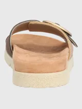 Sandalia marrón con tira ancha de tejido texturizado y hebilla circular decorativa.