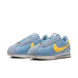 Championes Nike Cortez celestes con detalles en amarillo y suela blanca.