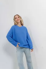 Sweater azul de punto medio, amplio, suave, con escote a la base y puños en mangas y en acabado inferior.