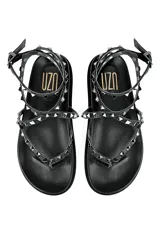 Sandalia plana de cuero color negro con tiras decoradas con tachas metálicas.