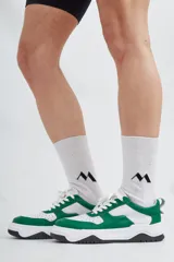 Zapatillas deportivas de cuero, combinadas en blanco y verde, con base negra.