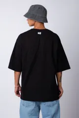 Remera verde militar de corte oversize, confeccionada en algodón 100% con cuello redondo y manga corta. Presenta un pequeño logo estampado en la parte superior de la espalda.