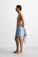 Bañador corto celeste de tejido técnico con cintura elástica ajustable con cordón interior y trabillas laterales. Cuenta con bolsillos frontales, bolsillo trasero con cierre de cremallera y forro interior.