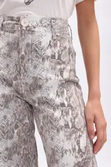 Pantalón de tiro alto, corte ancho y largo, con estampado de piel de serpiente en tonos beige y marrón. Presenta costuras visibles en color marrón oscuro.