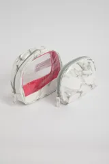 Set de dos necessaires de forma semicircular, con cierre superior y diseño marmolado en tonos grises y blancos. Uno de los necessaires es completamente opaco y el otro tiene la parte superior transparente con borde rosado.