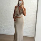 Conjunto color beige compuesto por un top halter con escote drapeado y una falda larga ajustada.