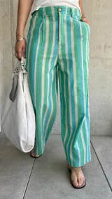 Pantalón de lino a rayas verticales en tonos verde, celeste y blanco, de corte holgado, con cierre y botón, y dos bolsillos laterales.