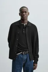 Cárdigan negro de punto con cuello solapa, manga larga y cierre frontal con botones.