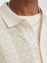 Polo de manga corta color crema con rayas verticales en relieve color verde claro. Tiene cuello clásico y cierre frontal con botones.