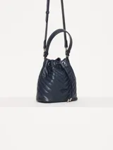Cartera tipo bucket azul marino con diseño matelaseado en forma de chevron. Tiene doble asa, una corta superior y otra larga regulable para usar al hombro o cruzada. El cierre es con cordón ajustable.