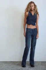 Jeans de mezclilla azul oscuro con efecto lavado, tiro bajo y pierna ancha extra larga. Modelo de cinco bolsillos con cierre frontal de cremallera y botón metálico.