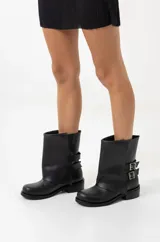 Botas de cuero negro con caña baja, botamanga y hebillas laterales.