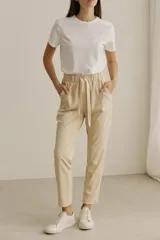 Pantalón babucha color beige, de simil cuero, con cintura elastizada y lazo ajustable.