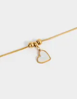 Pulsera dorada de acero inoxidable con dije de corazón de nácar y cadena extensible.