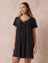 Camisón corto negro con lunares blancos, de tejido suave y escote redondo con detalle plisado y moño blanco.