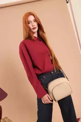 Bandolera de cuero sintético color beige, con diseño compacto y elegante. Cuenta con un bolsillo frontal con cierre y un compartimento principal con cierre. La correa es regulable.