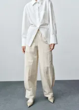 Pantalón de vestir color crema, de corte ancho y tiro medio, con cintura elástica y pinzas en el bajo.