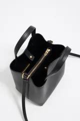 Bolso tote pequeño de cuero sintético color negro con doble asa de mano y correa bandolera ajustable y extraíble. Logotipo de la marca en letras doradas en la parte frontal.