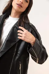 Cazadora negra de cuero sintético estilo biker, con cuello solapa, cierre cruzado con cremallera, bolsillos laterales con cremallera y trabillas en los hombros.