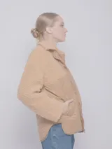 Campera de corderito negro con piezas de nylon capitoneado, con tres bolsillos y botones a presión.