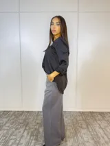 Blusa negra de satén con escote en V y mangas largas con puños abotonados.