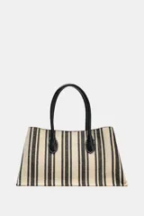 Bolso tipo shopper de mano de lona color crudo con rayas verticales negras y asas de cuero sintético negro. Tiene tira interior con cierre de mosquetón metálico, bolsillo interior con cierre de cremallera y cierre imantado.